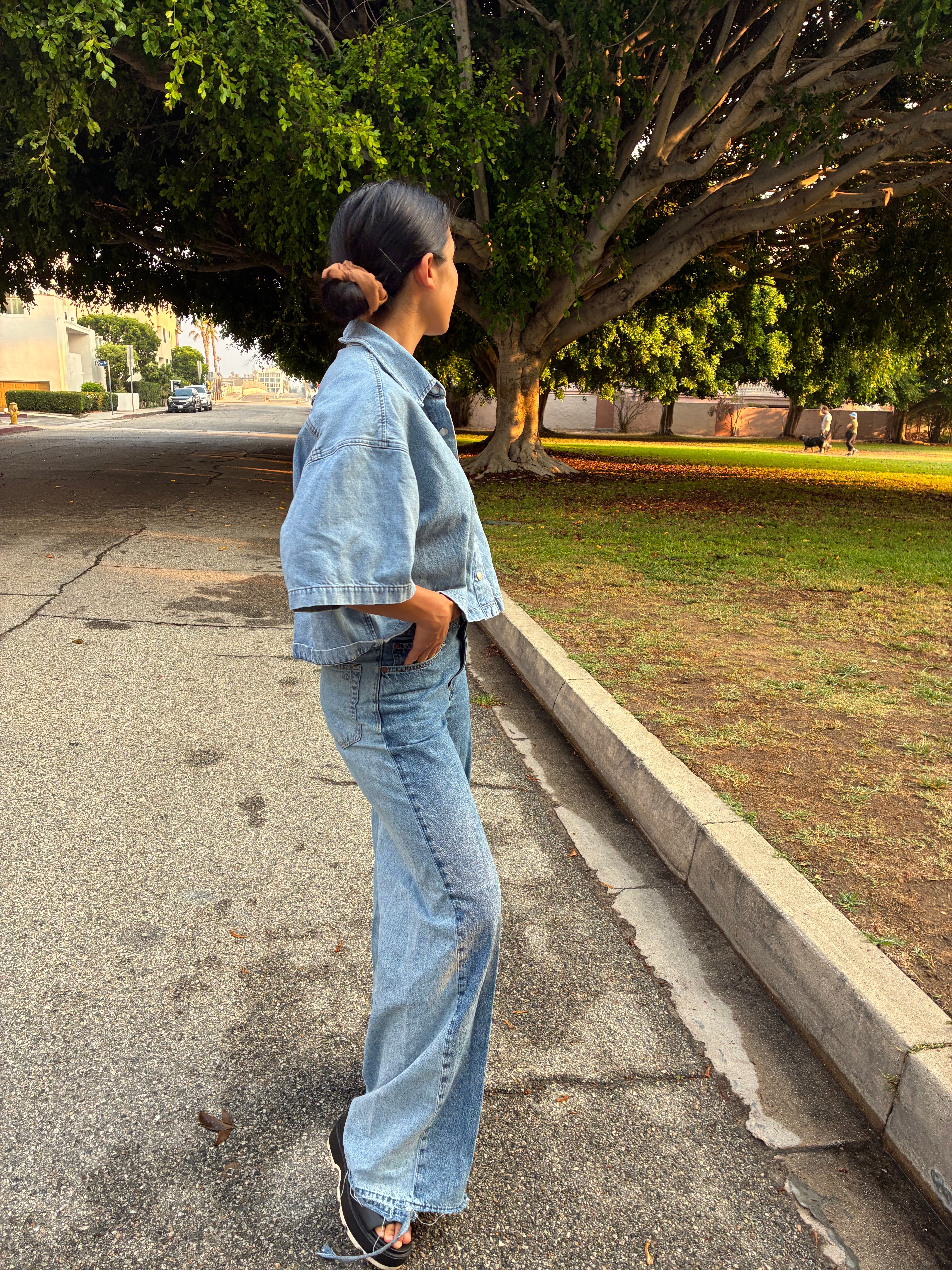 A woman poses in a stylish outfit of loose-fitting denim jeans and top.